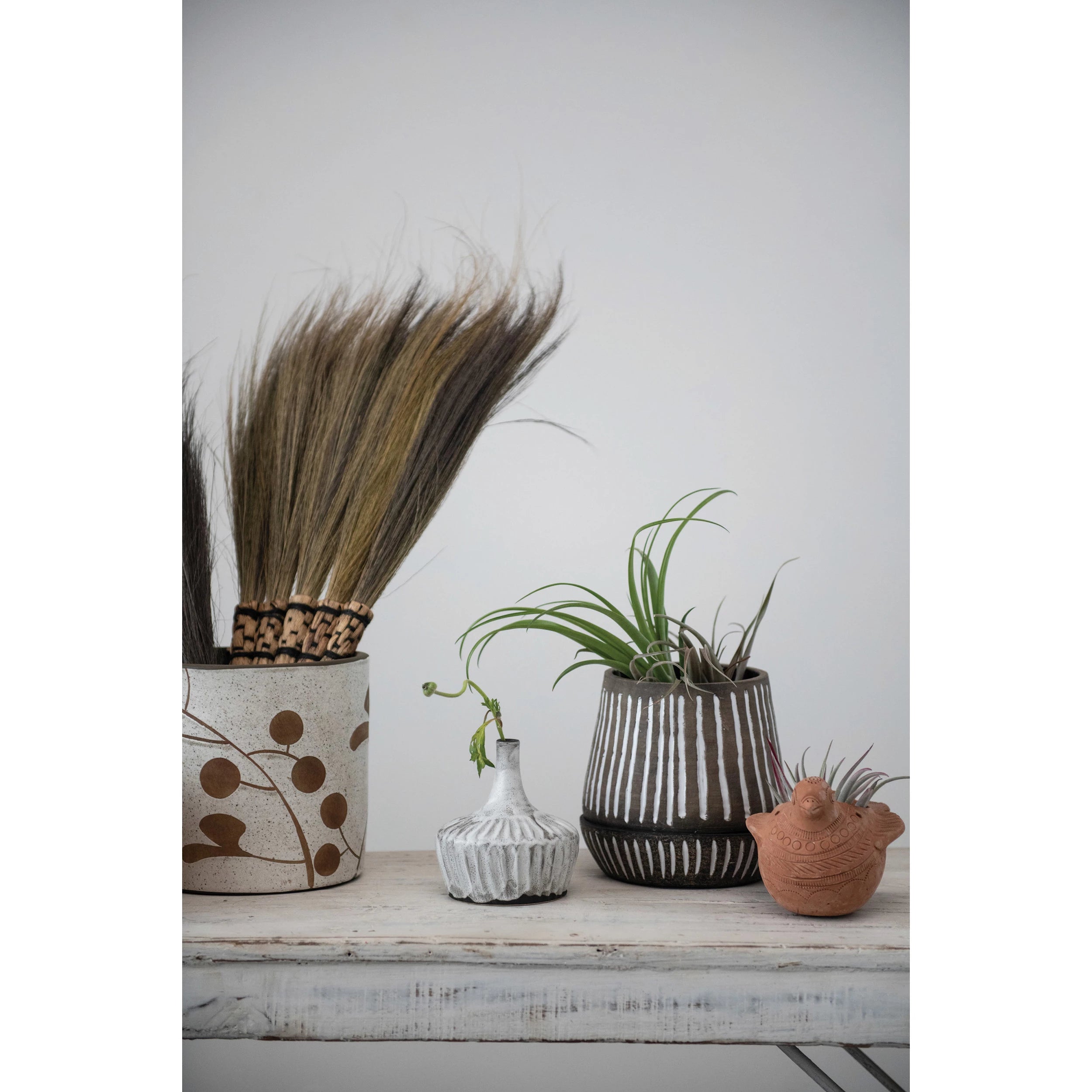 A brown terracotta pot with white stripes pattern, including a saucer, displayed against a white background.